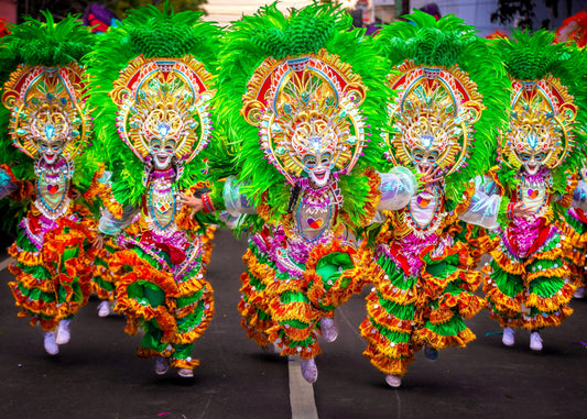 A vibrant group of people in colorful costumes and feathers celebrating a Filipino festival in the UK.