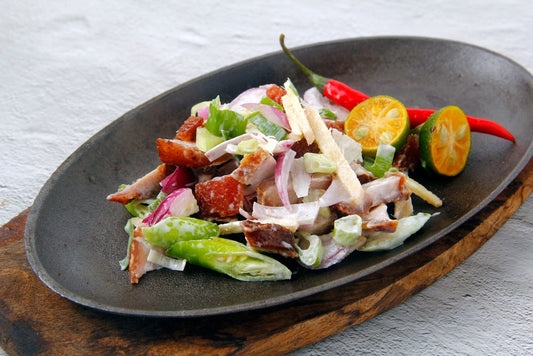 Close-up of Dinakdakan, showcasing tender pork mixed with onions and chili, garnished for a colorful presentation.