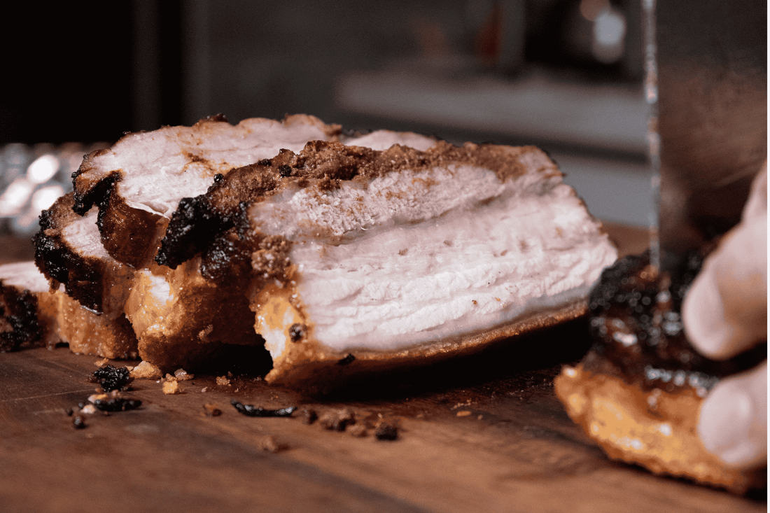  Close-up of a person cutting pork bagnet, highlighting its crispy skin and tender meat on a rustic cutting board.