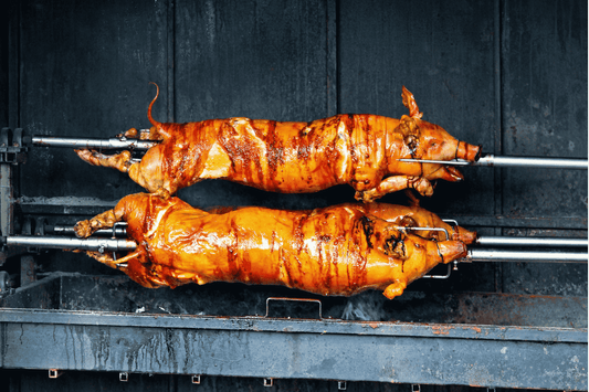 Two pigs being grilled, highlighting lechon baboy, a beloved Filipino delicacy famous for its savory flavor and festive appeal.