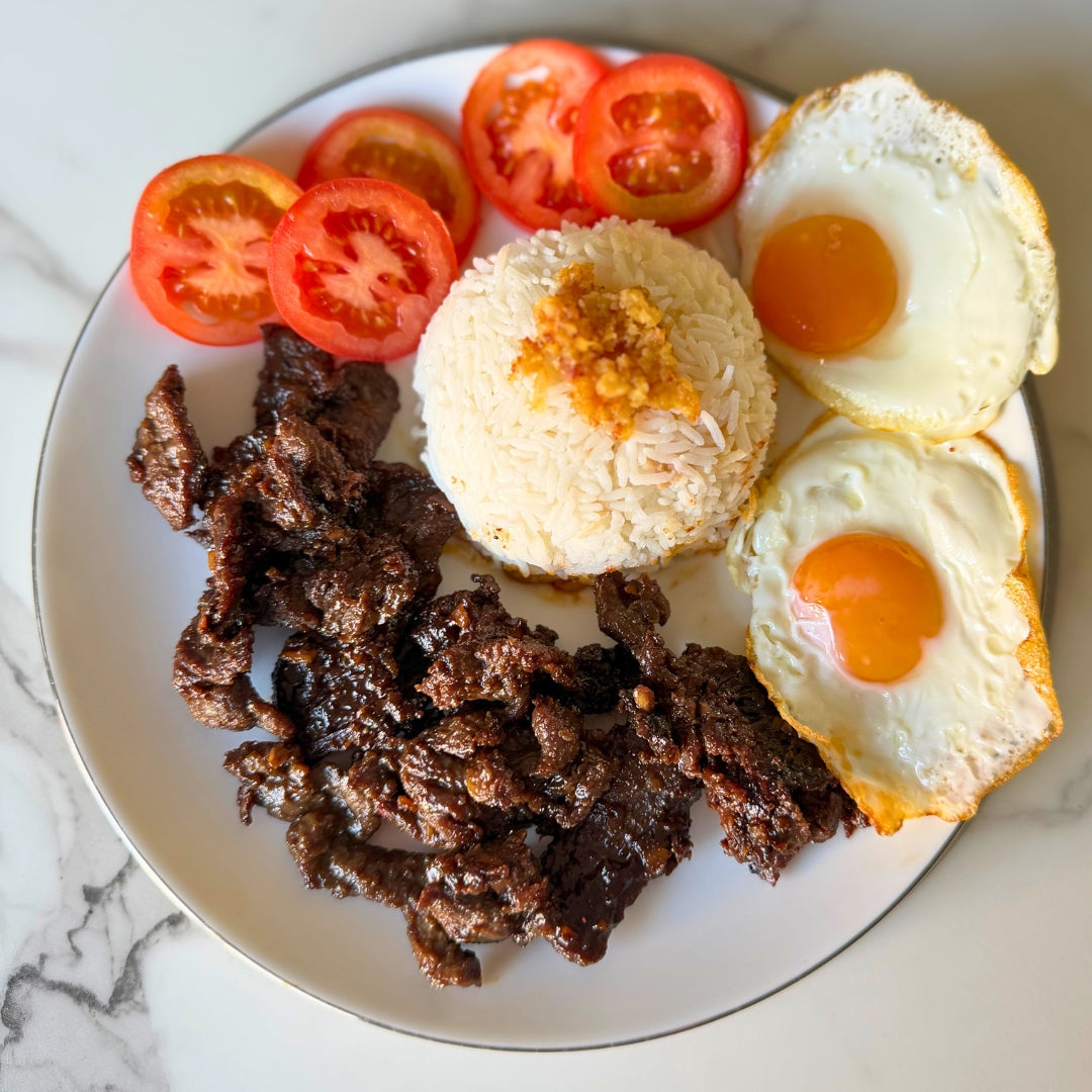 Plate of food with eggs, beef tapa and tomatoes 