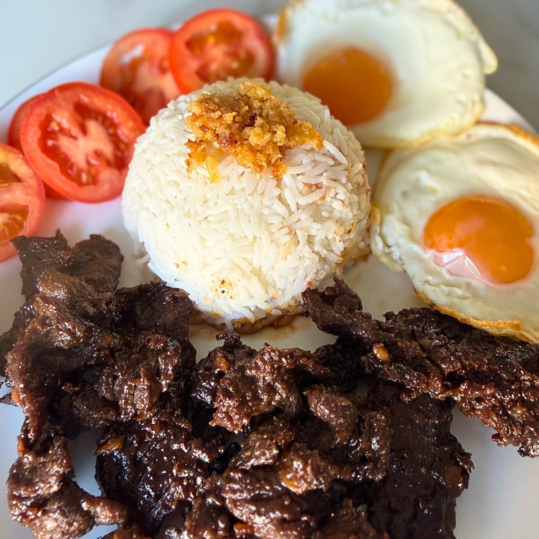 Plate of food with eggs, beef tapa and tomatoes 